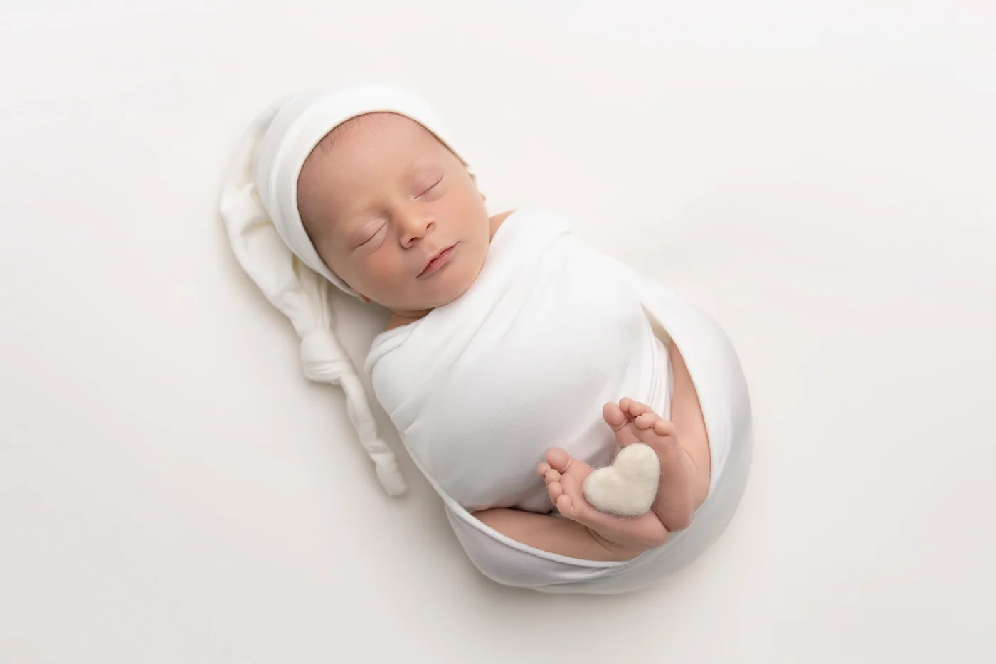 Newborn swaddled in white on a soft blue runner