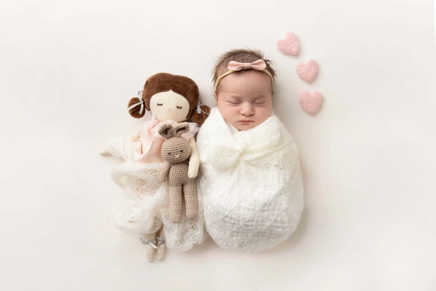 Newborn in lace on a blush backdrop with felt hearts